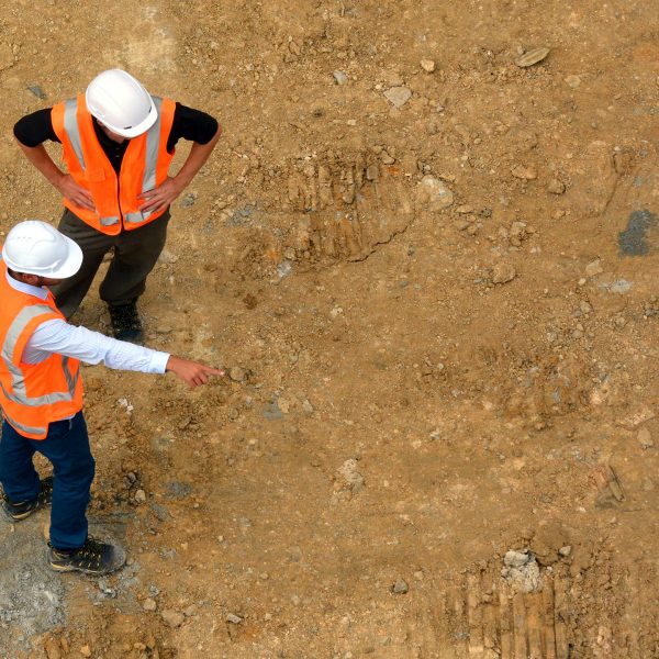 Aerial view of two unrecognized civil engineers inspecting an empty new construction site. Building development concept. Candid photo. Real people. Copy space